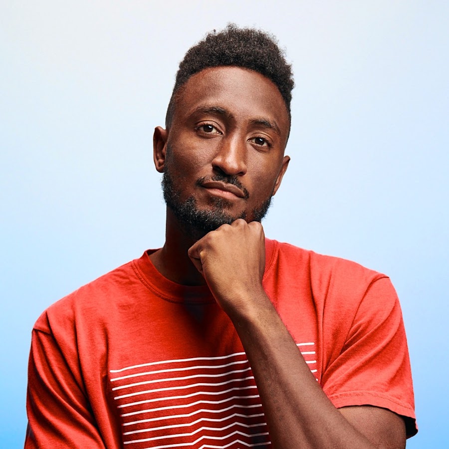 O avatar do canal MKBHD: Marques Brownlee com uma camiseta vermelha listrada, o punho no queixo, sobre um fundo azul claro